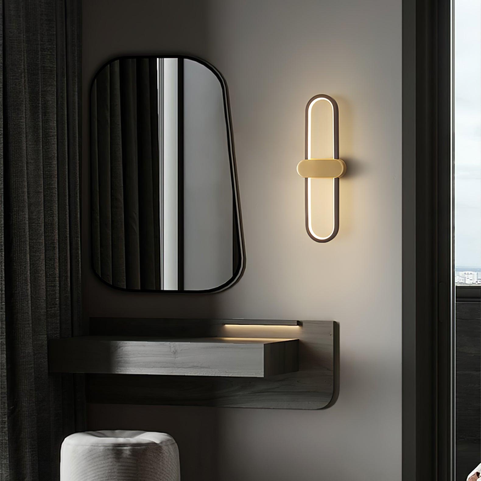 Black oval wall light with gold-coloured centre beside a mirror and curtain above a dresser