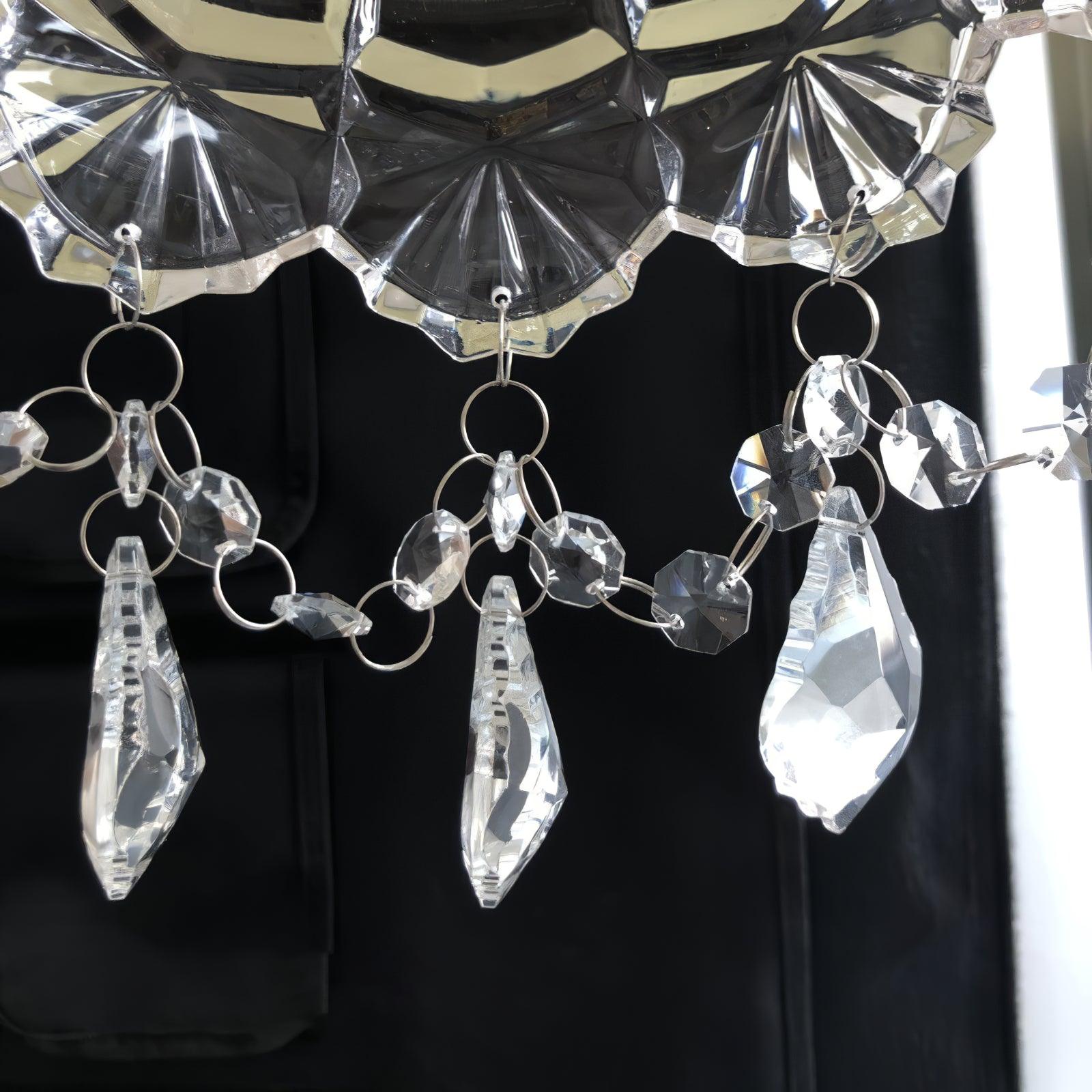 Close scalloped clear shade rim, metal loops, faceted beads and hanging drops against a dark background