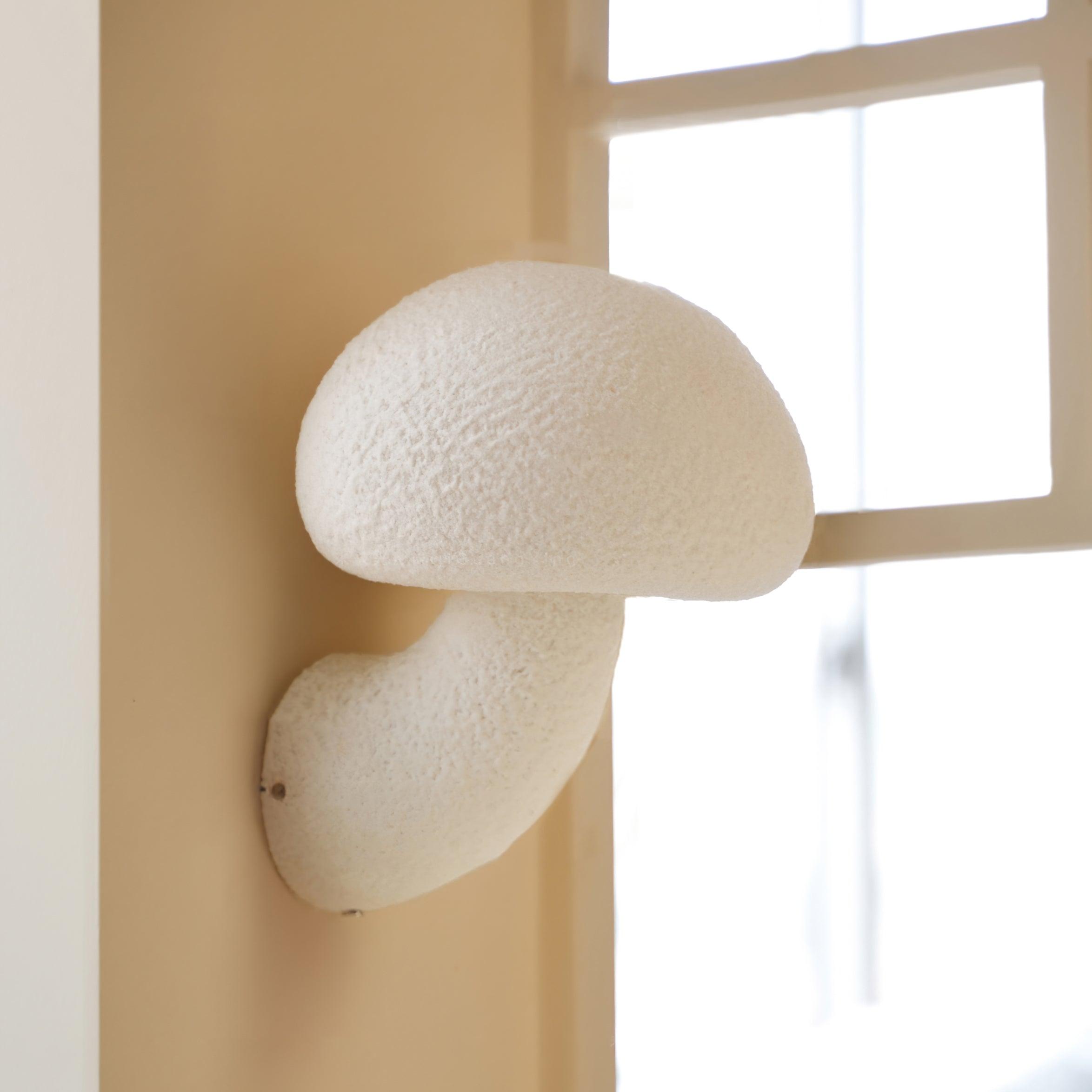 White mushroom wall light next to a window