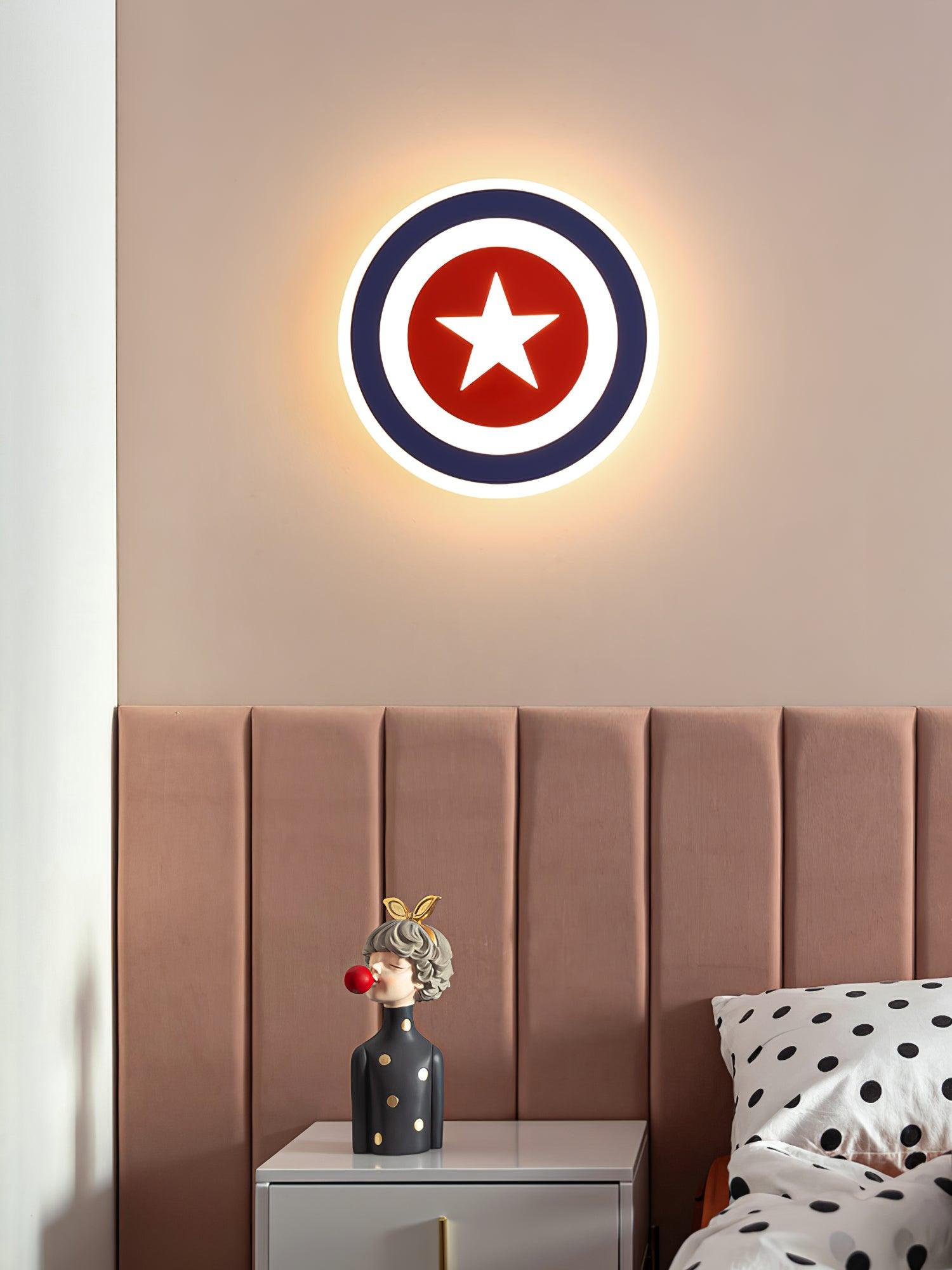 Blue-ring star wall lamp above pink panelled headboard, bedside figurine and polka-dot bedding