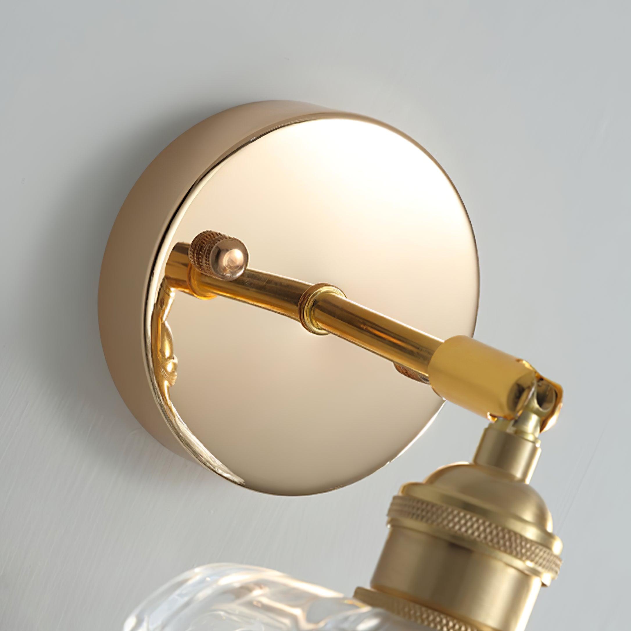 Close gold-tone round wall plate, short arm, end joint and bulb-holder top above the clear shade
