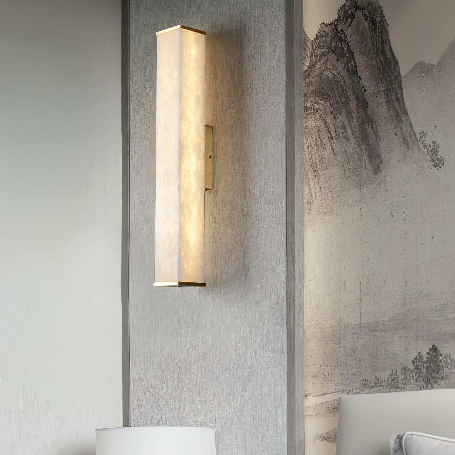 Closer view of an illuminated alabaster wall light beside mountain artwork and a pale headboard