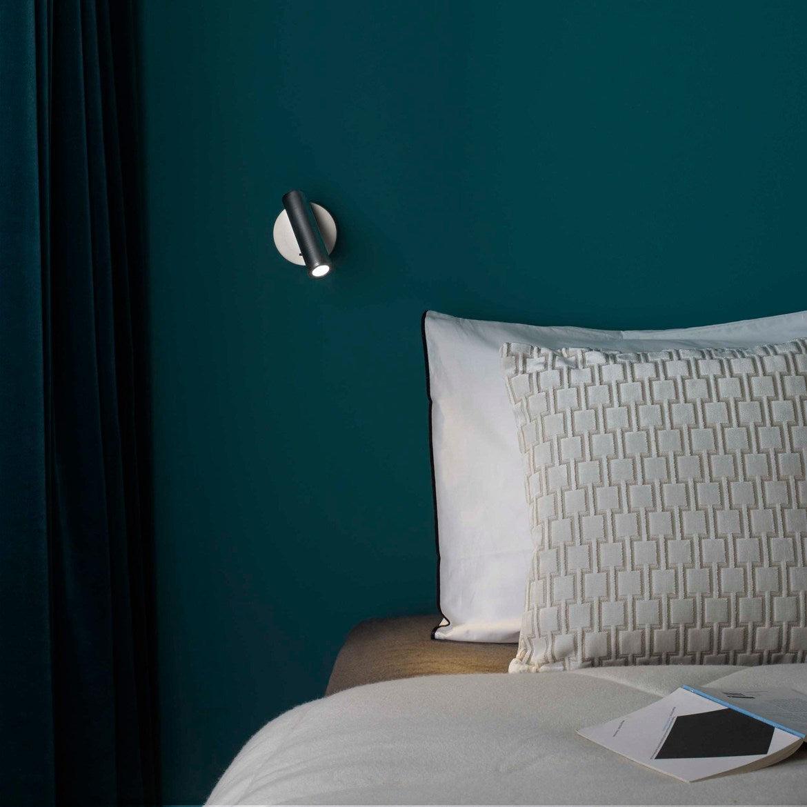 Small metallic reading lamp on a blue wall