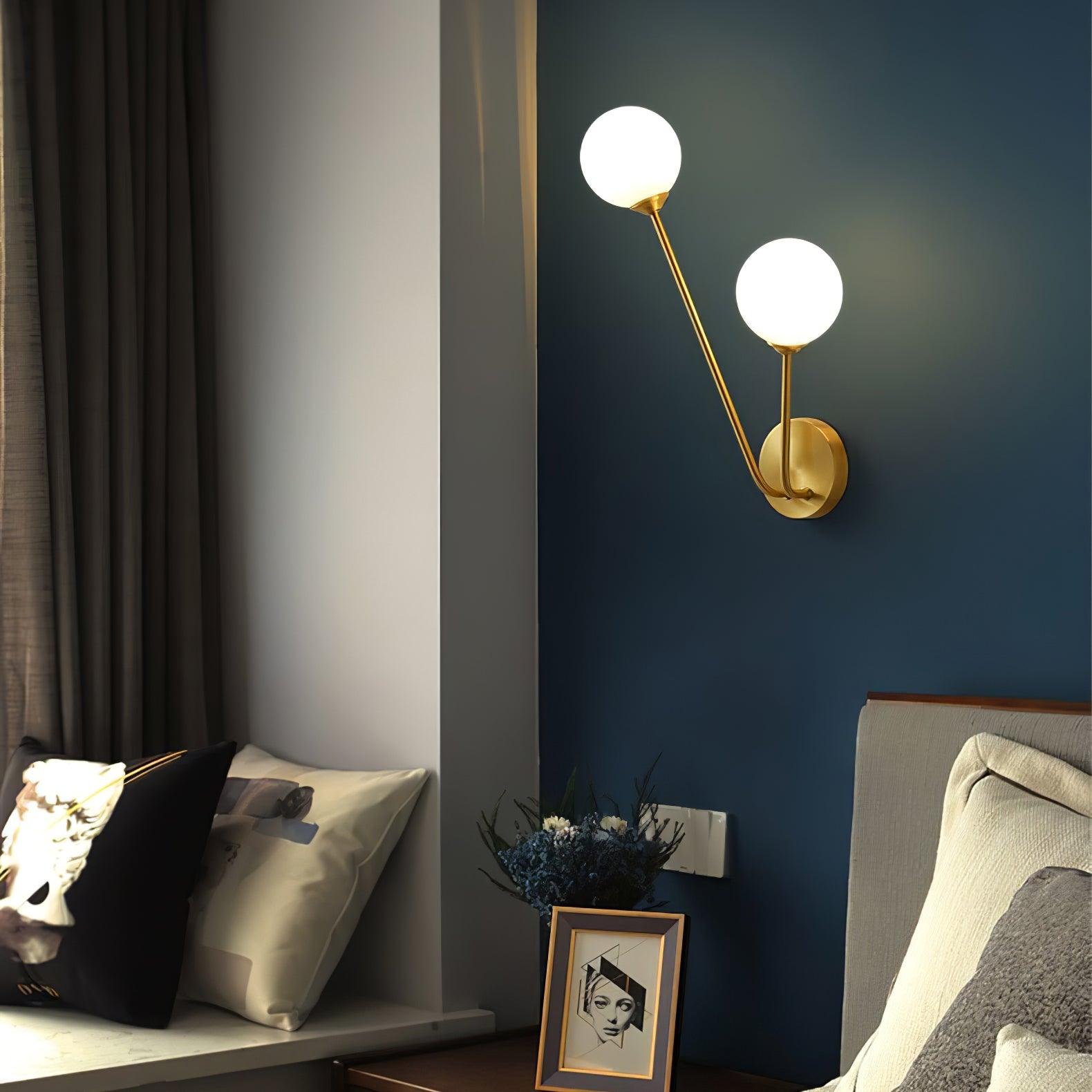 Angled white globe wall light on a dark blue bedroom wall near framed art and flowers