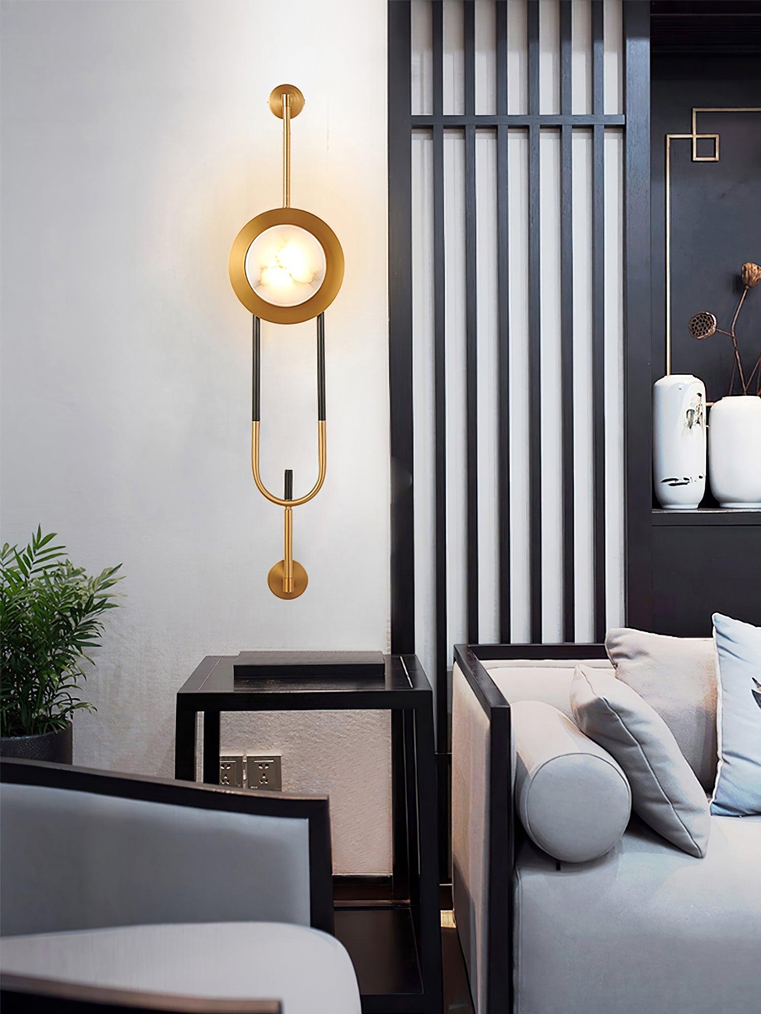 Wide room view of the lit marble wall light beside a slatted divider, sofa and glass-topped table