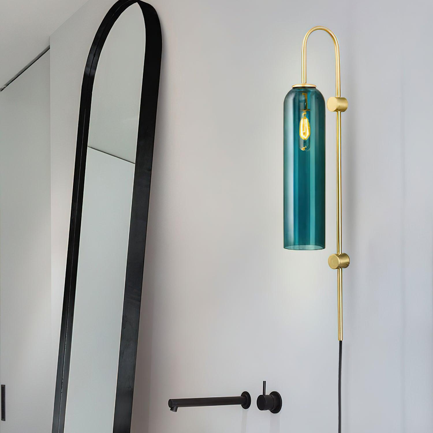 Dark teal glass wall fixture beside an arched mirror