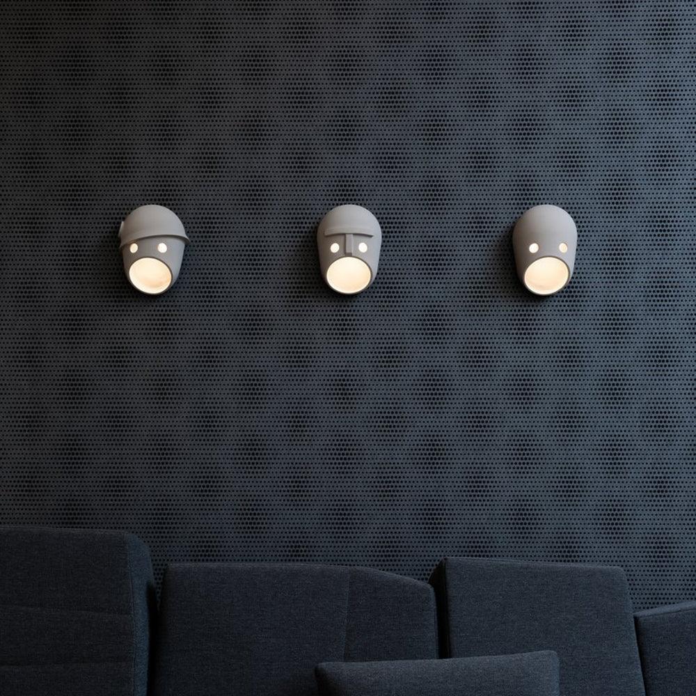 Three illuminated Mask face lights above a dark sofa