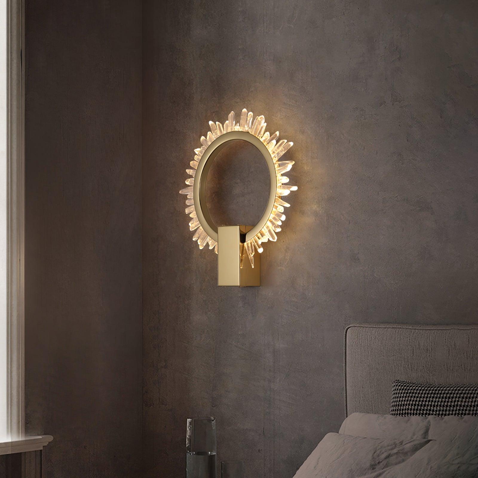 Gold crystal ring wall light on a textured grey wall beside a bedhead near a window