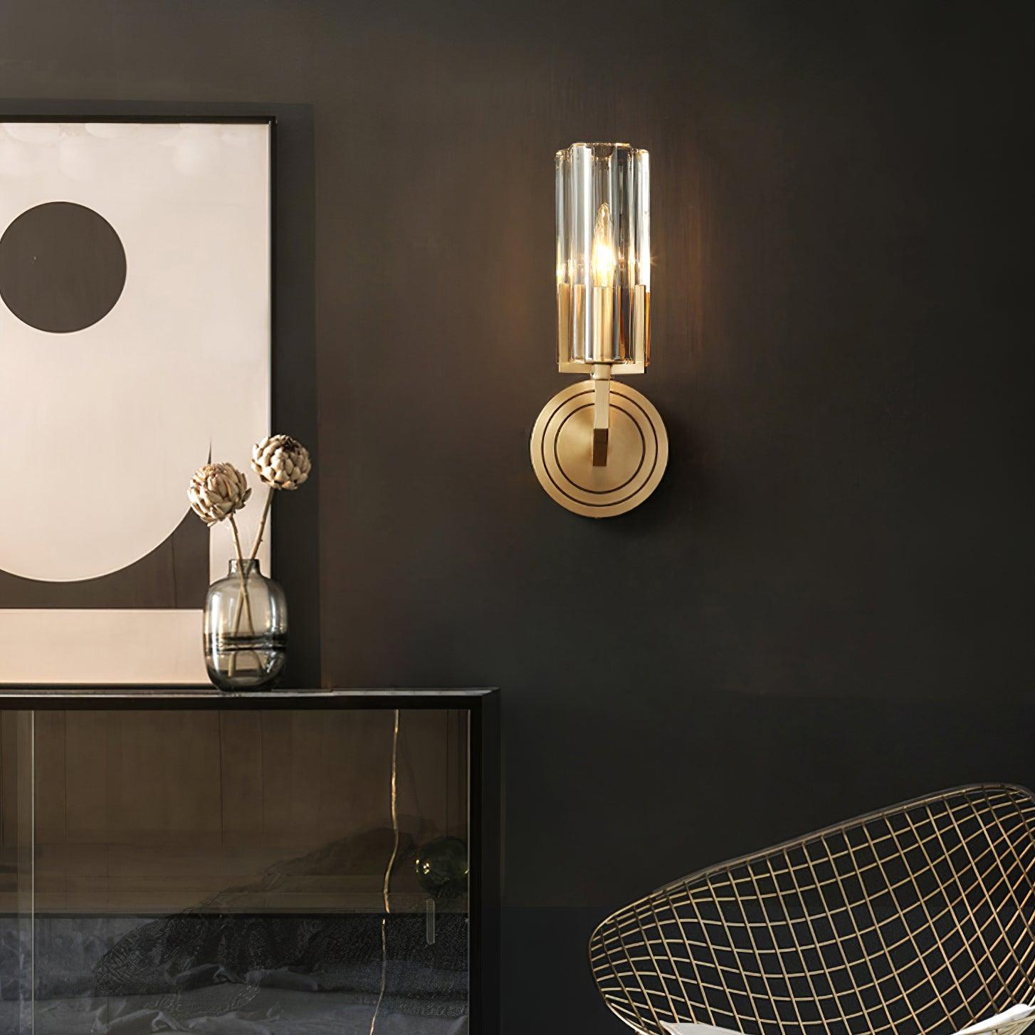 Single-shade Kayla on dark wall above glass-front cabinet beside abstract circle print, flower vase and wire chair