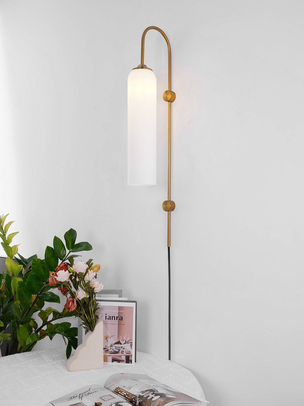 White cylindrical wall shade beside a bed