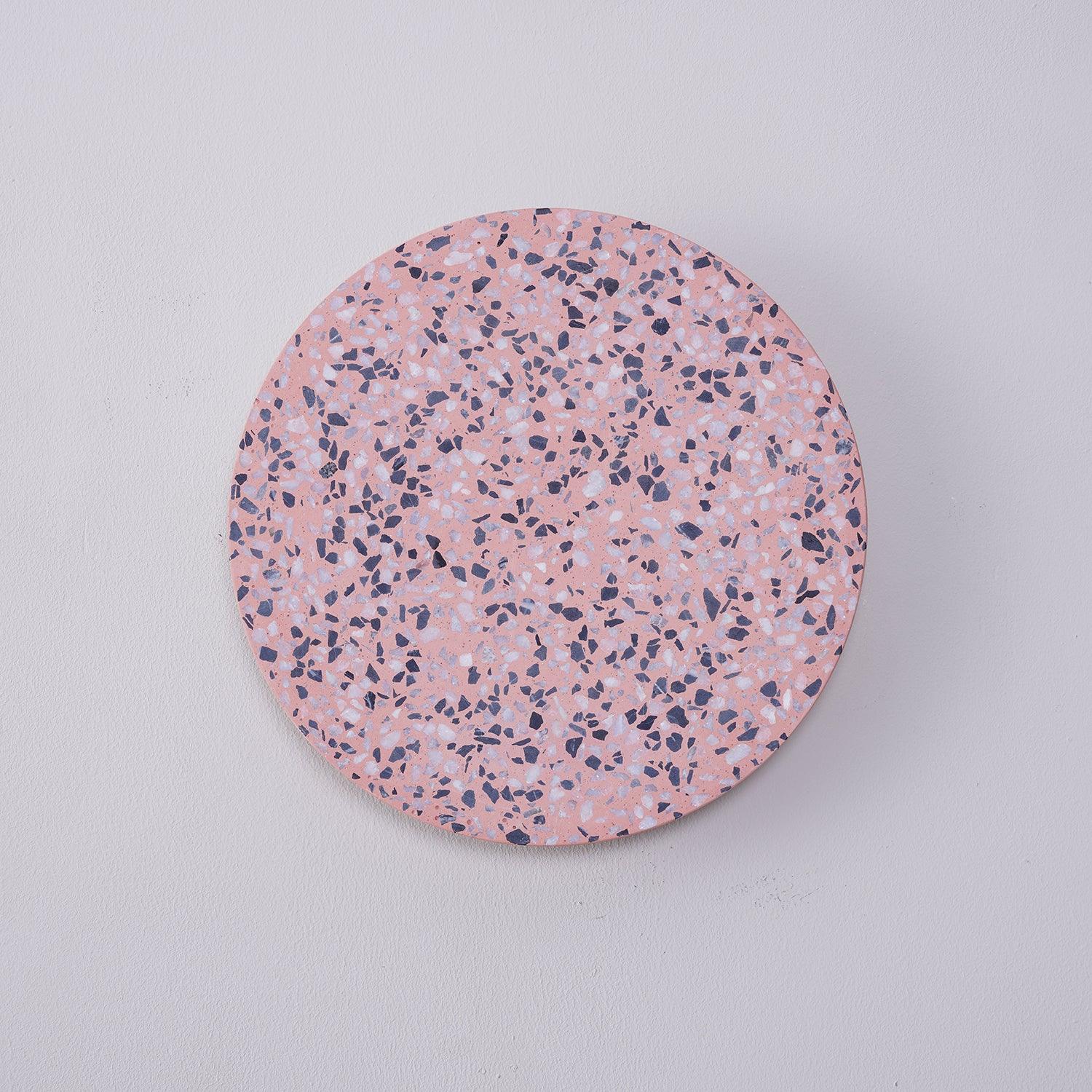 Pink terrazzo disc in an unlit wall view