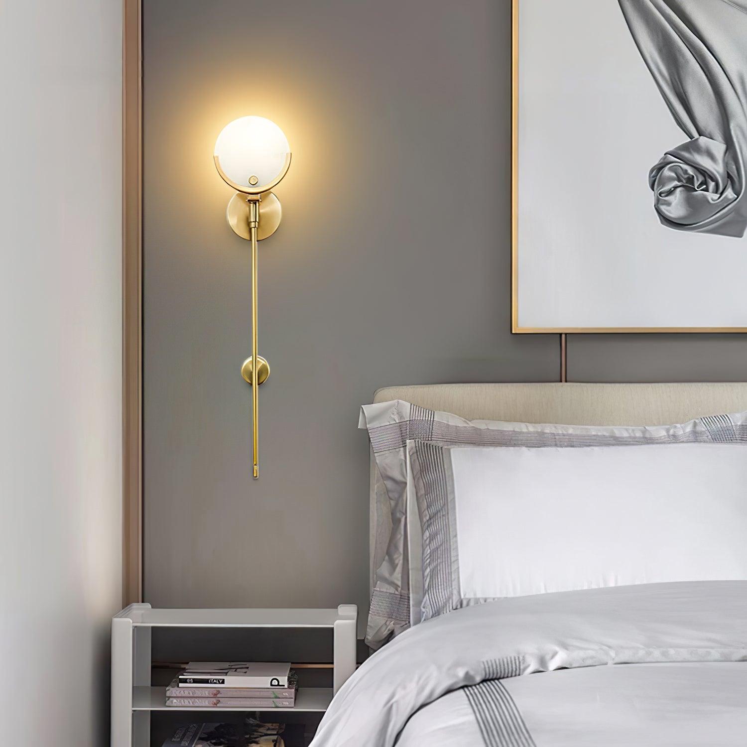 Lit long-stem Ava wall light beside white pillows and framed artwork above an open bedside bookstand