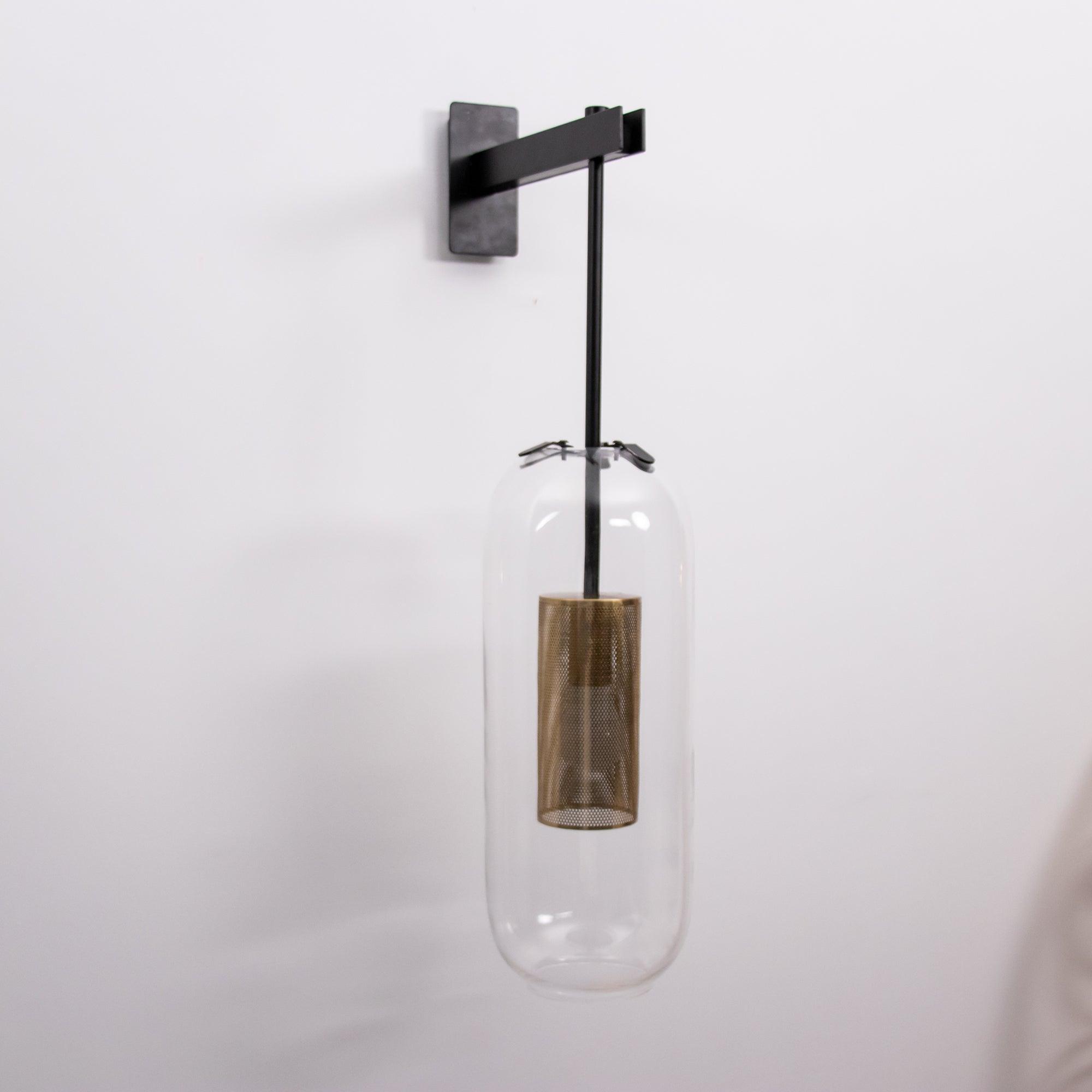 Unlit glass capsule beneath a Black arm