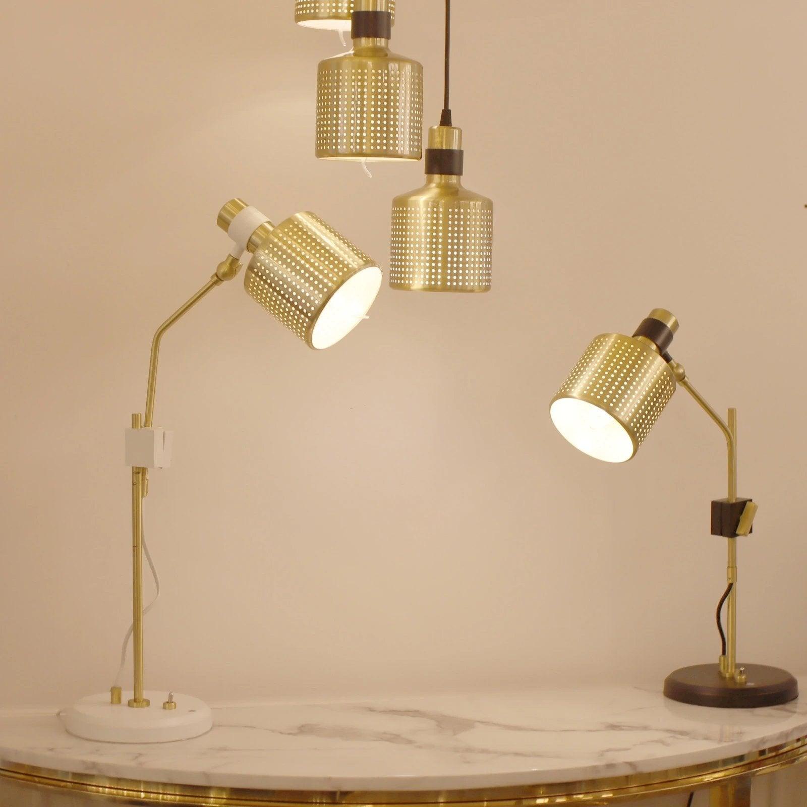 Gold-and-white and gold-and-black table lamps on a marble counter beneath three separate gold pendant lights
