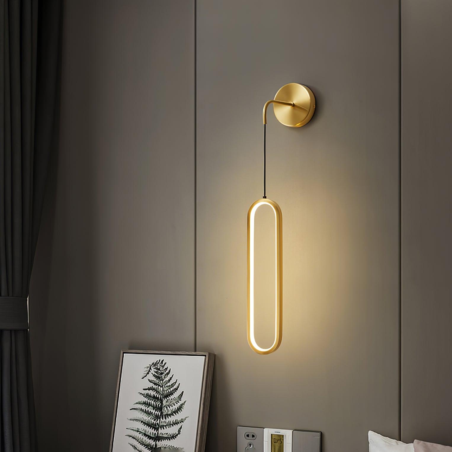 Brass oval wall light above a bedside cabinet