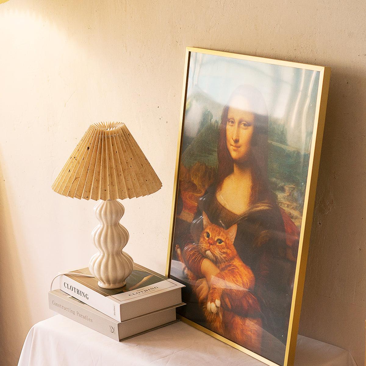Leo lamp on stacked books beside framed artwork