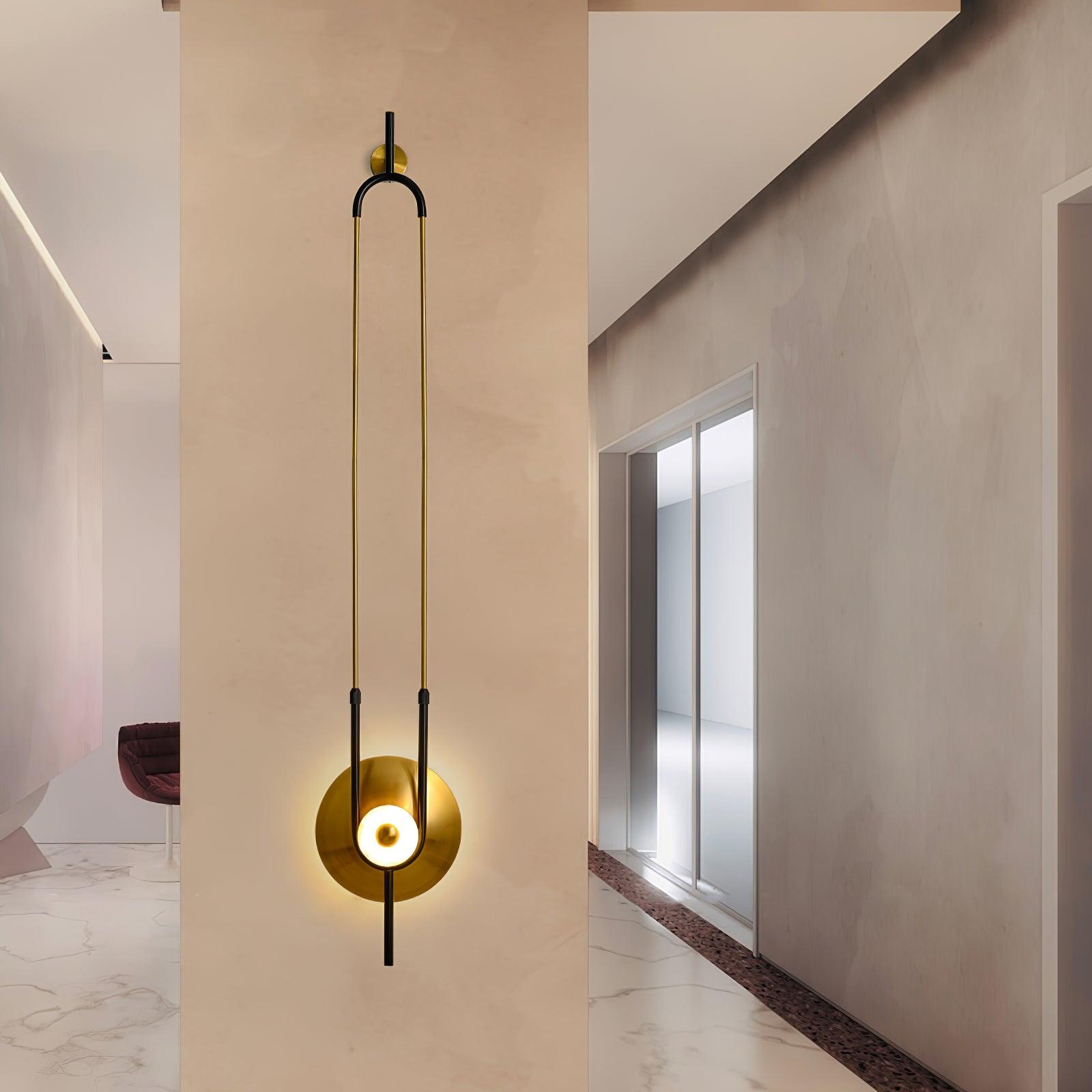 Tall loop wall light on pale corridor divider beside frosted doors, with red chair and veined floor beyond