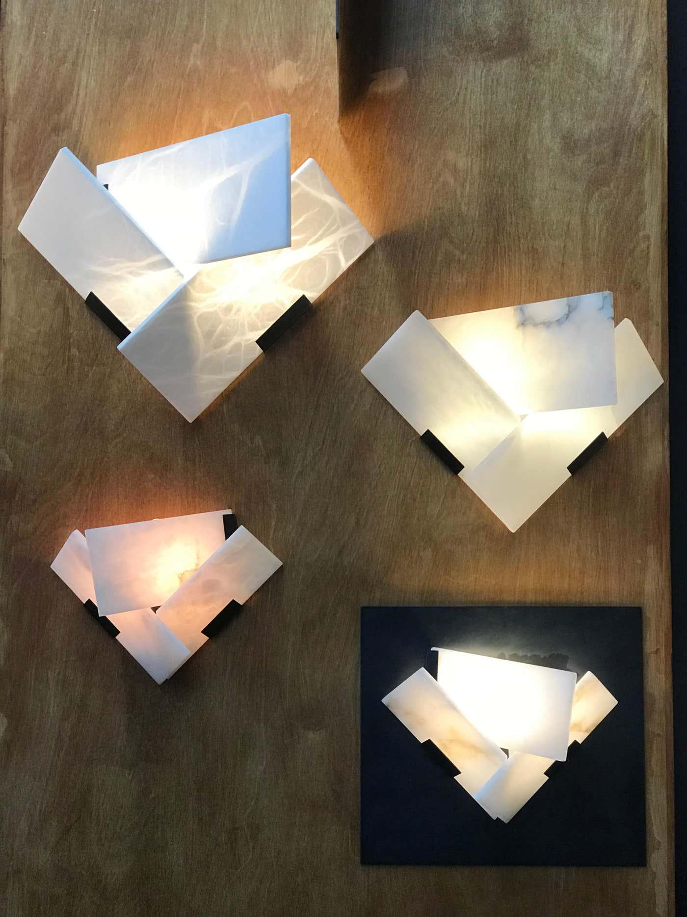 Four illuminated angular alabaster fixtures at different positions on a wood-paneled wall