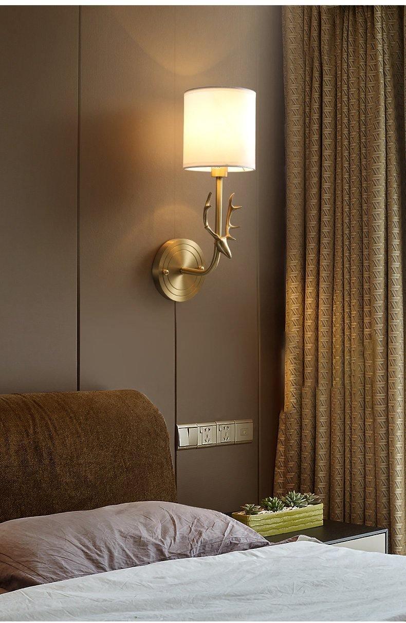 Single-shade brass sconce beside a bed
