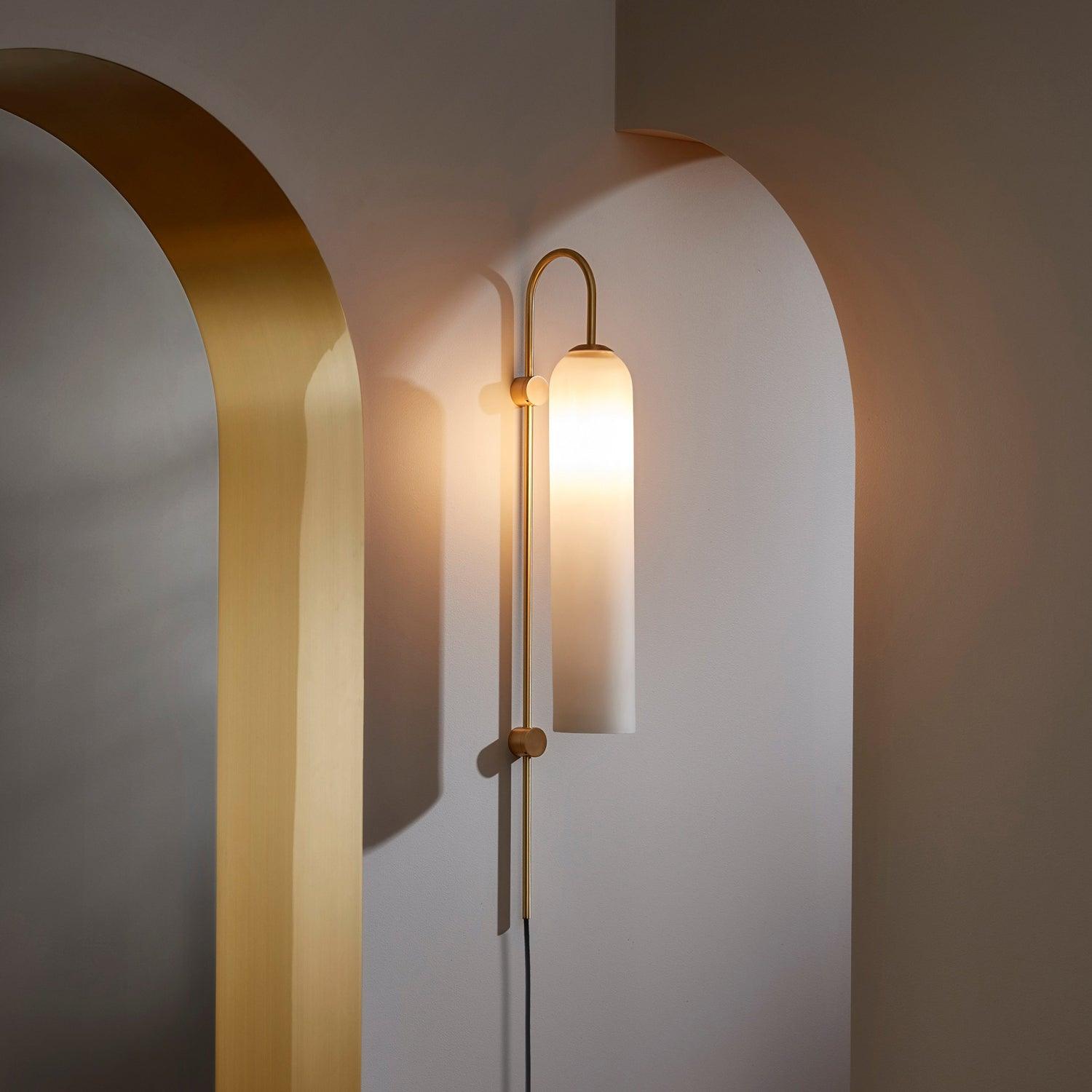 Tall white glass wall lamp beside a curved doorway