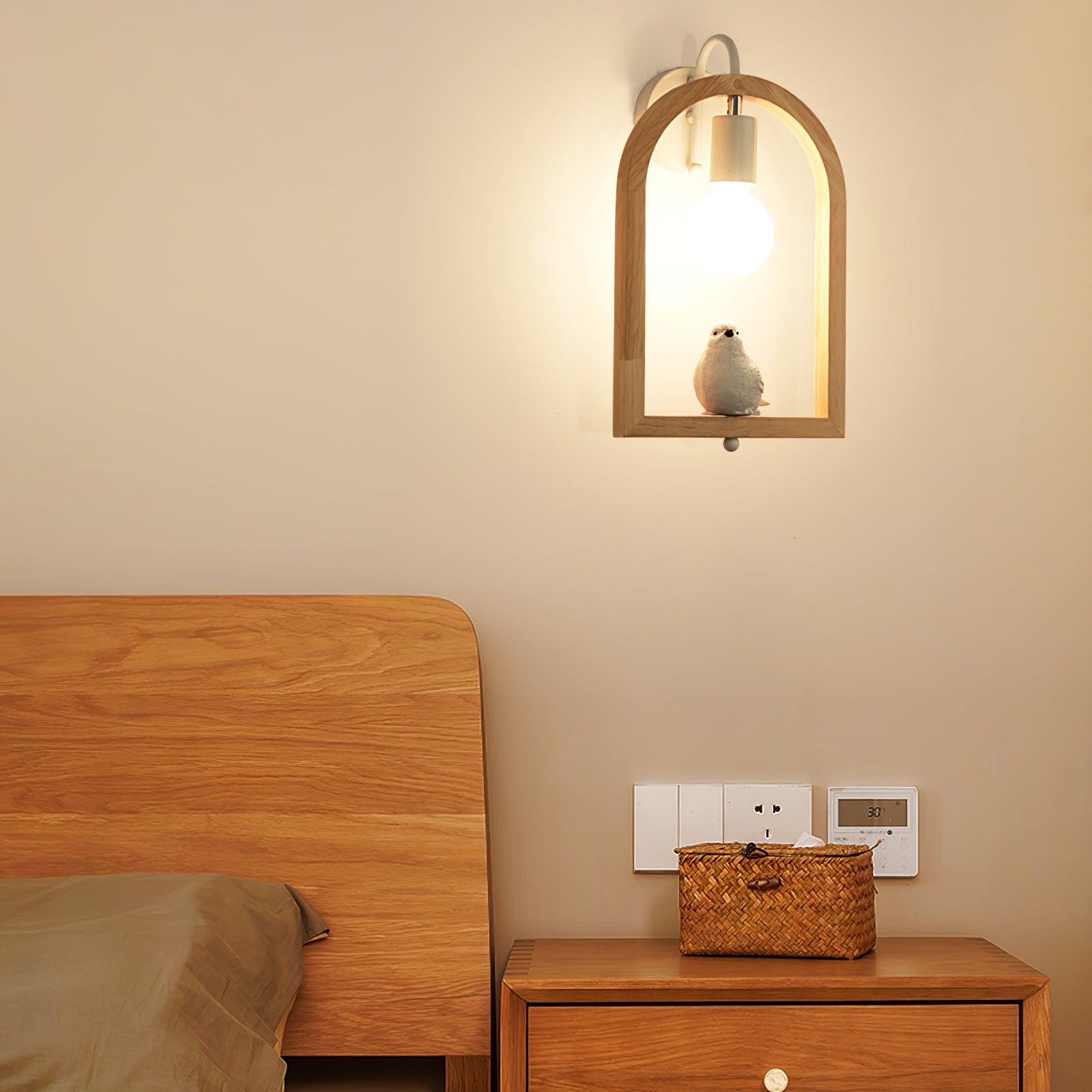 Bird wall lamp above a bedside cabinet with a woven basket, beside a wooden headboard and wall control panel