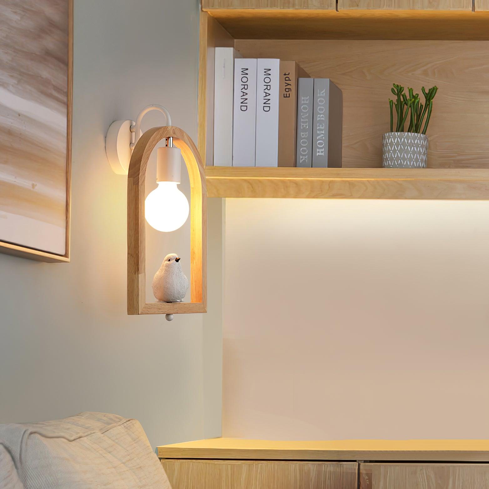Bird wall light beside wooden shelving with books and a potted plant, with a chair and cabinet below