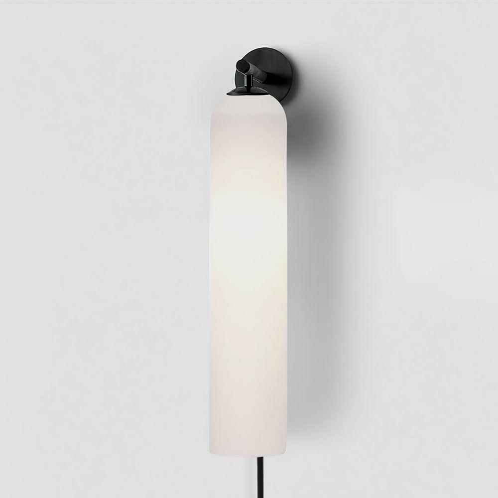 Milky white cylindrical shade beneath a black wall fitting