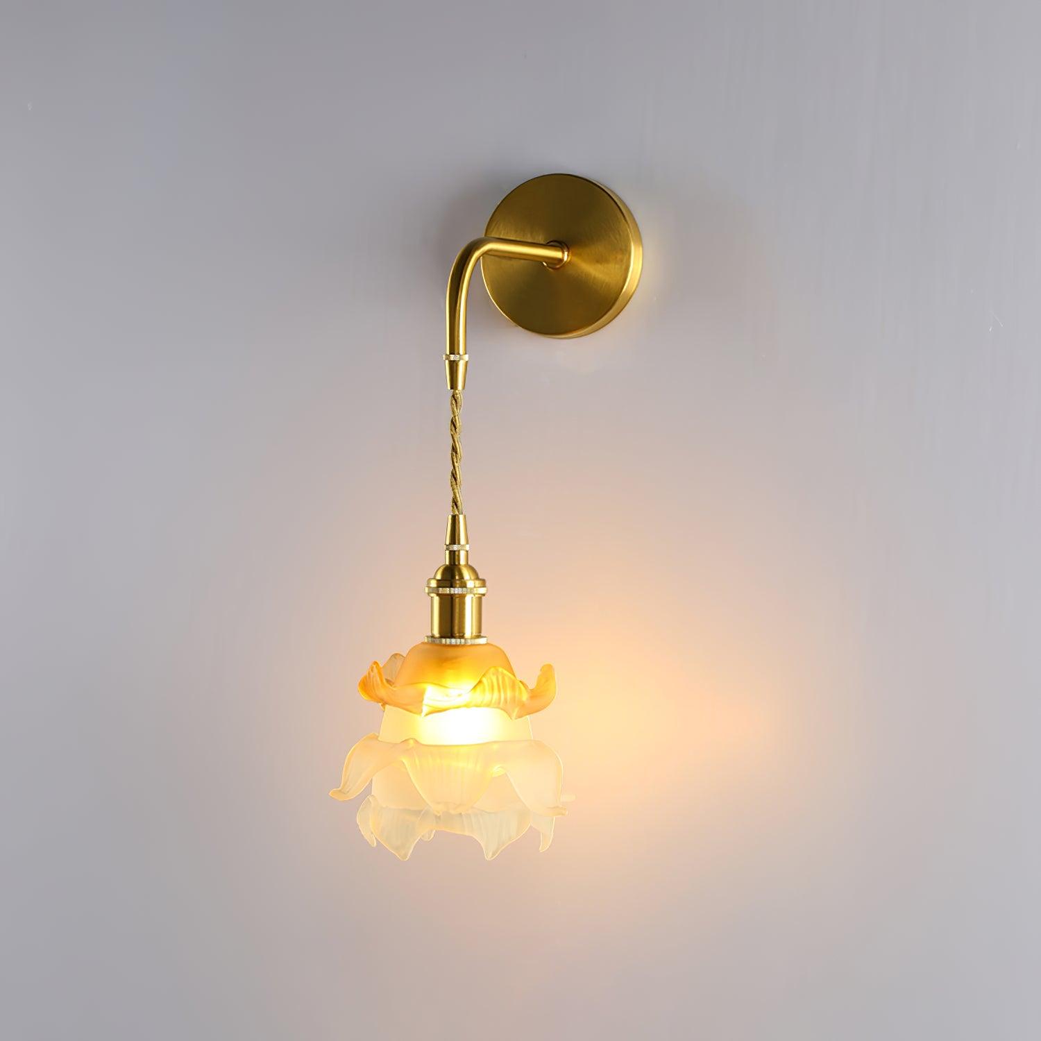 White and orange floral glass shade glowing beneath a brass wall arm