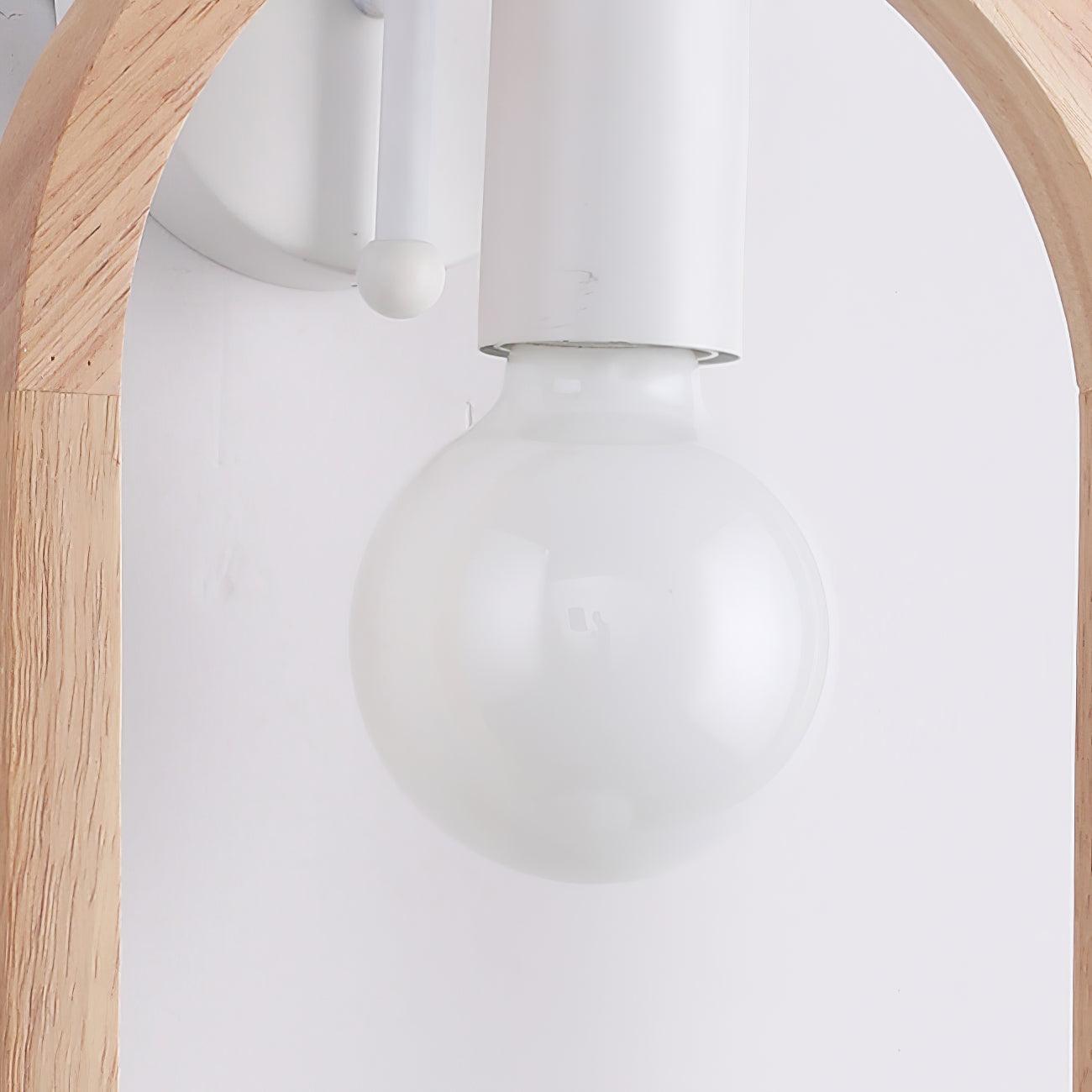 Close-up of an unlit white globe bulb in its cylindrical holder, with the wooden arch and white bracket behind