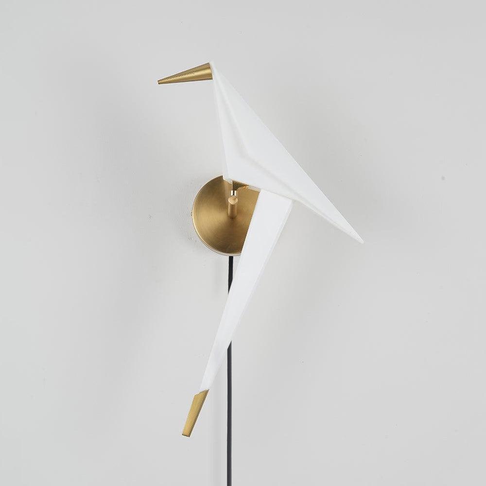 Profile of the unlit-looking White bird wall lamp with Gold beak, tail tip and round backplate, with a cable below