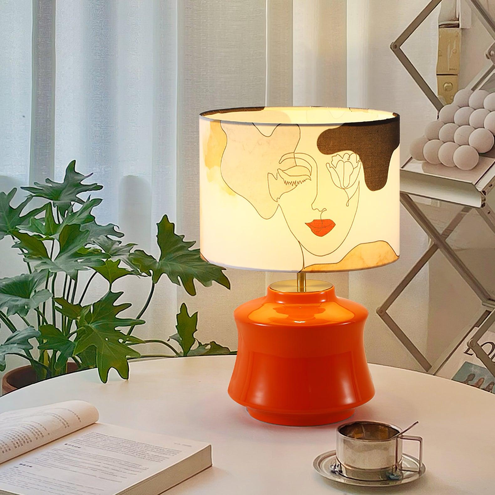Marilyn graphic-shade lamp on a round wooden table with a cup