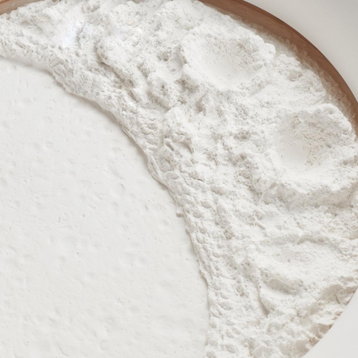Close-up of unlit white gypsum moon relief, showing irregular craters, raised ridge and curved surround edge
