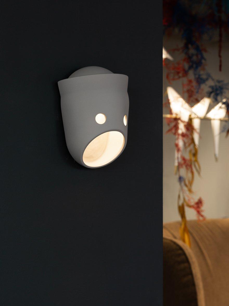 Illuminated face wall light with a raised top rim