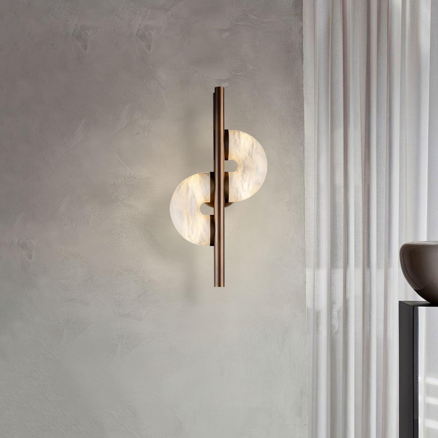 Wider view of glowing stone discs and bronze bar near white curtain above a cropped brown vase and dark console