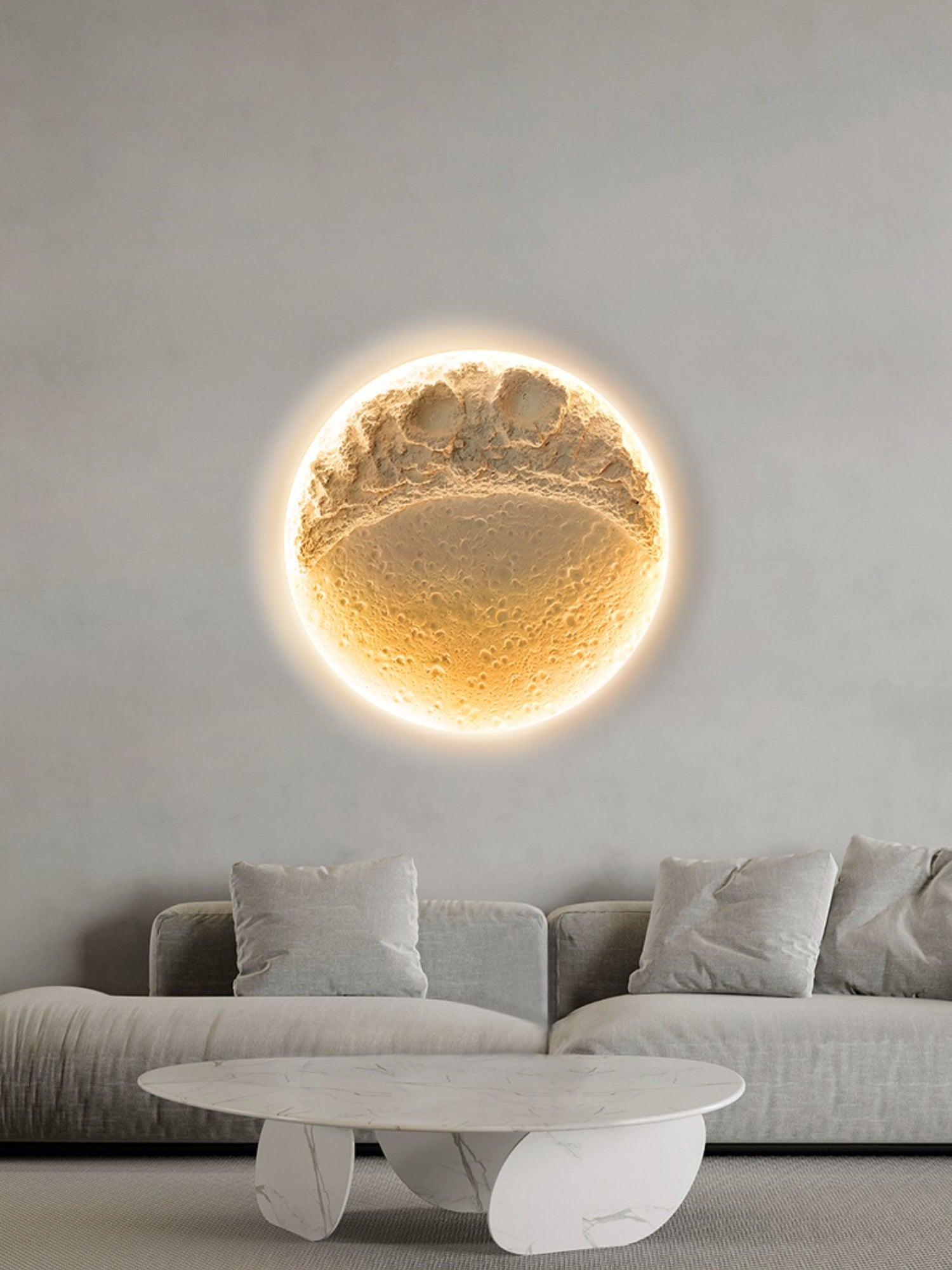 Front view of lit moon relief above cream sofa and low oval table, showing fine pits below larger upper craters