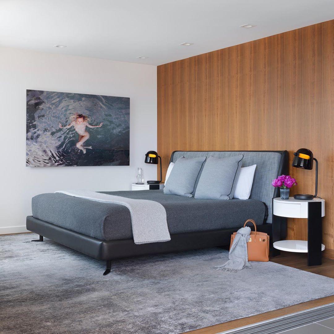 Mona lamps beside a bed with a blue upholstered headboard