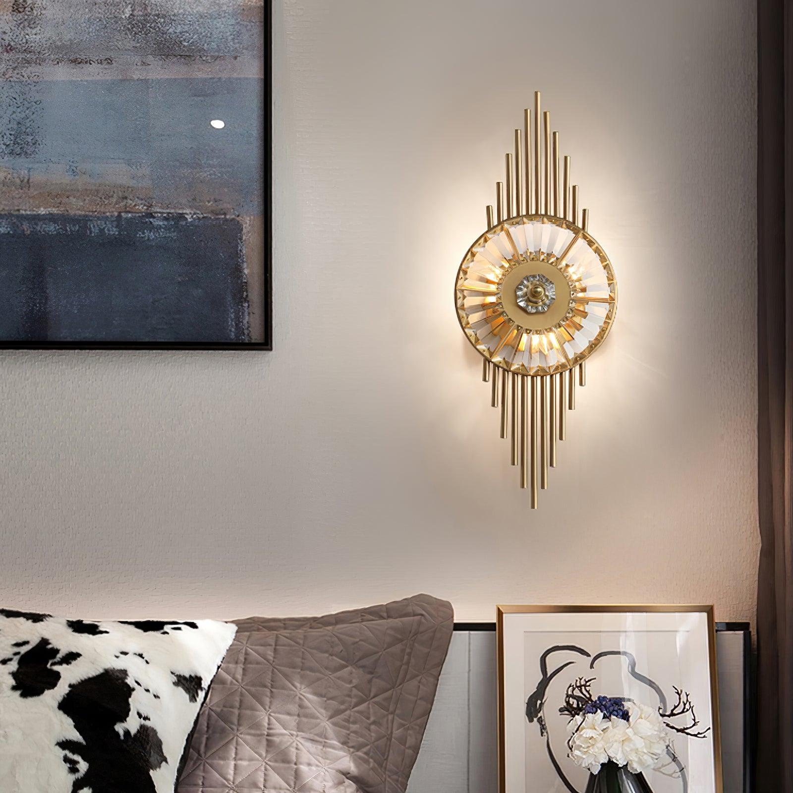 Gold crystal glass wall light glowing above quilted cushions beside framed artwork and flowers