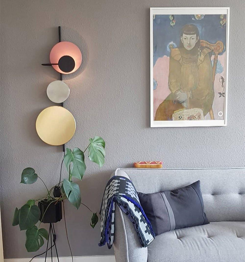 Disc wall light beside a sofa and framed art