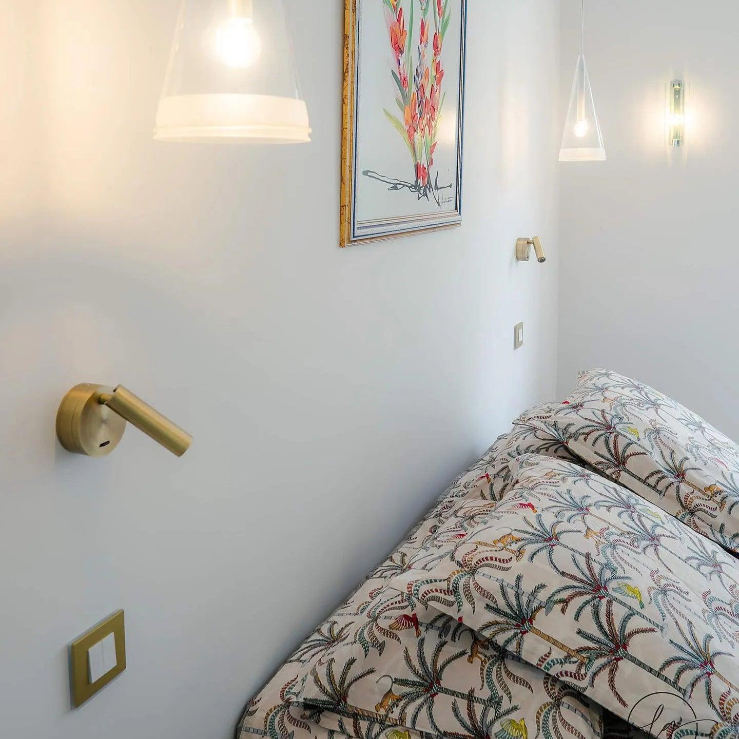 Metal reading spotlight beside patterned bedding