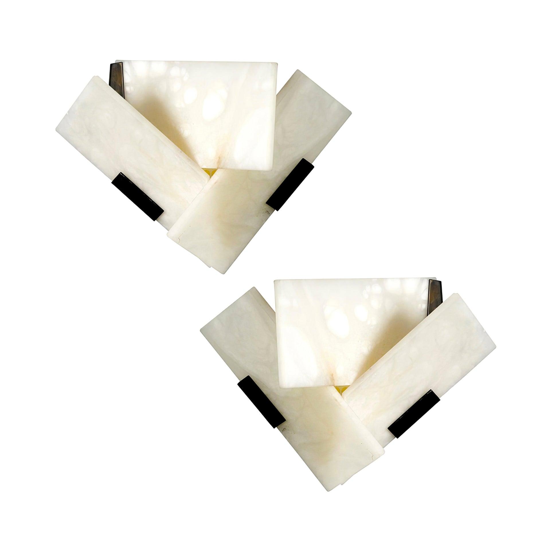 Two illuminated mirrored alabaster sconces arranged diagonally on white