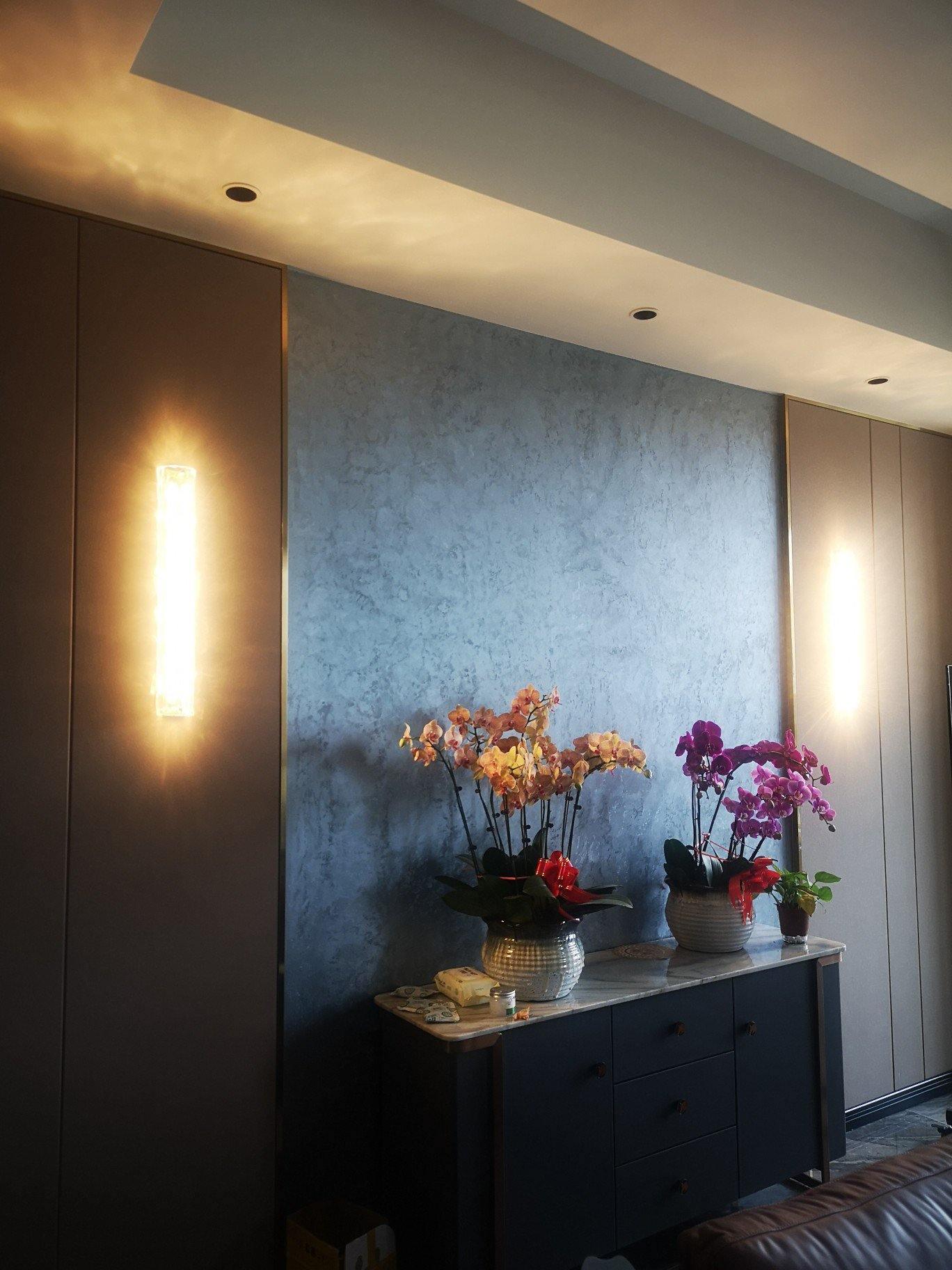 Lit wall-light arrangement around a dresser and flowers