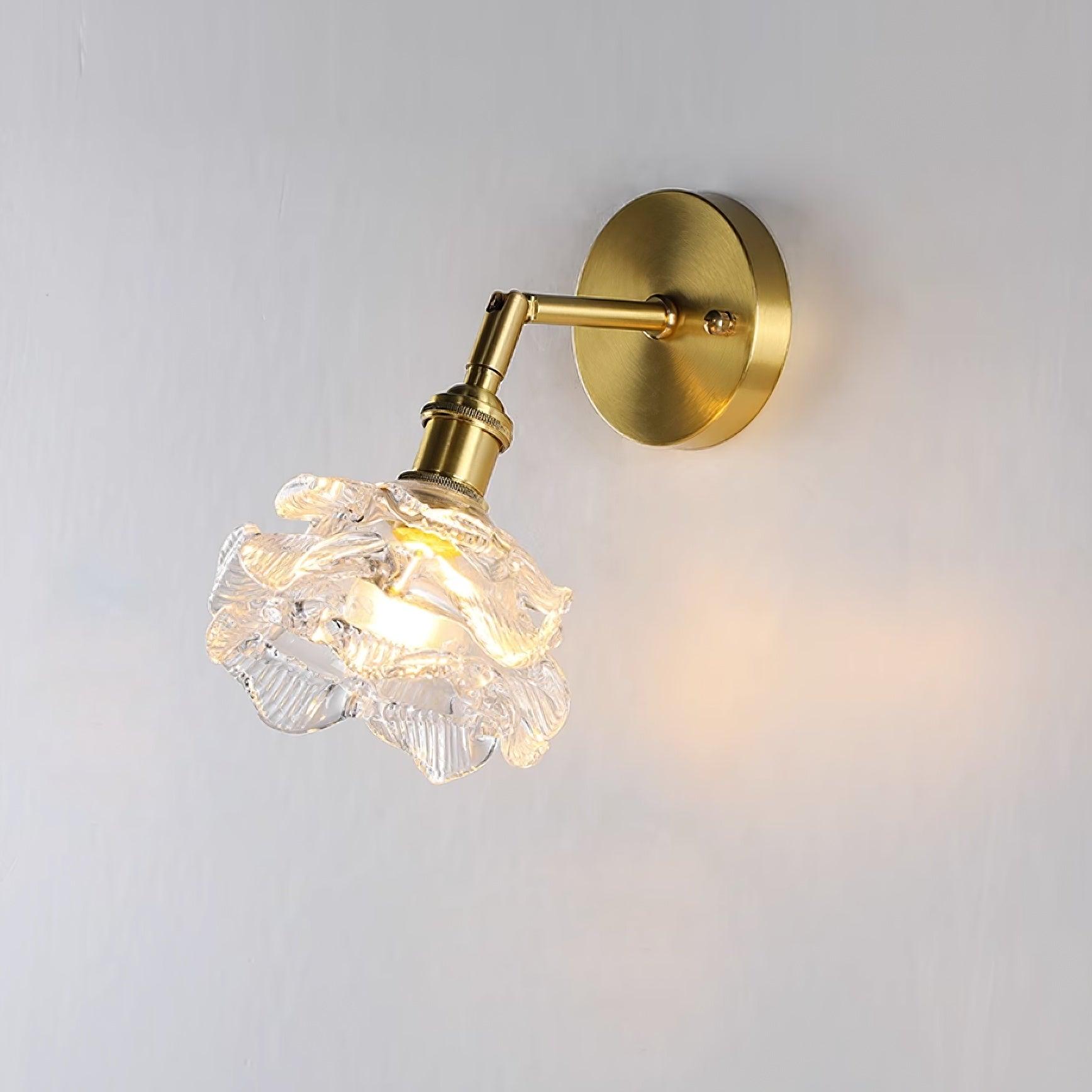 Lit Kano brass-and-clear wall lamp on a grey wall