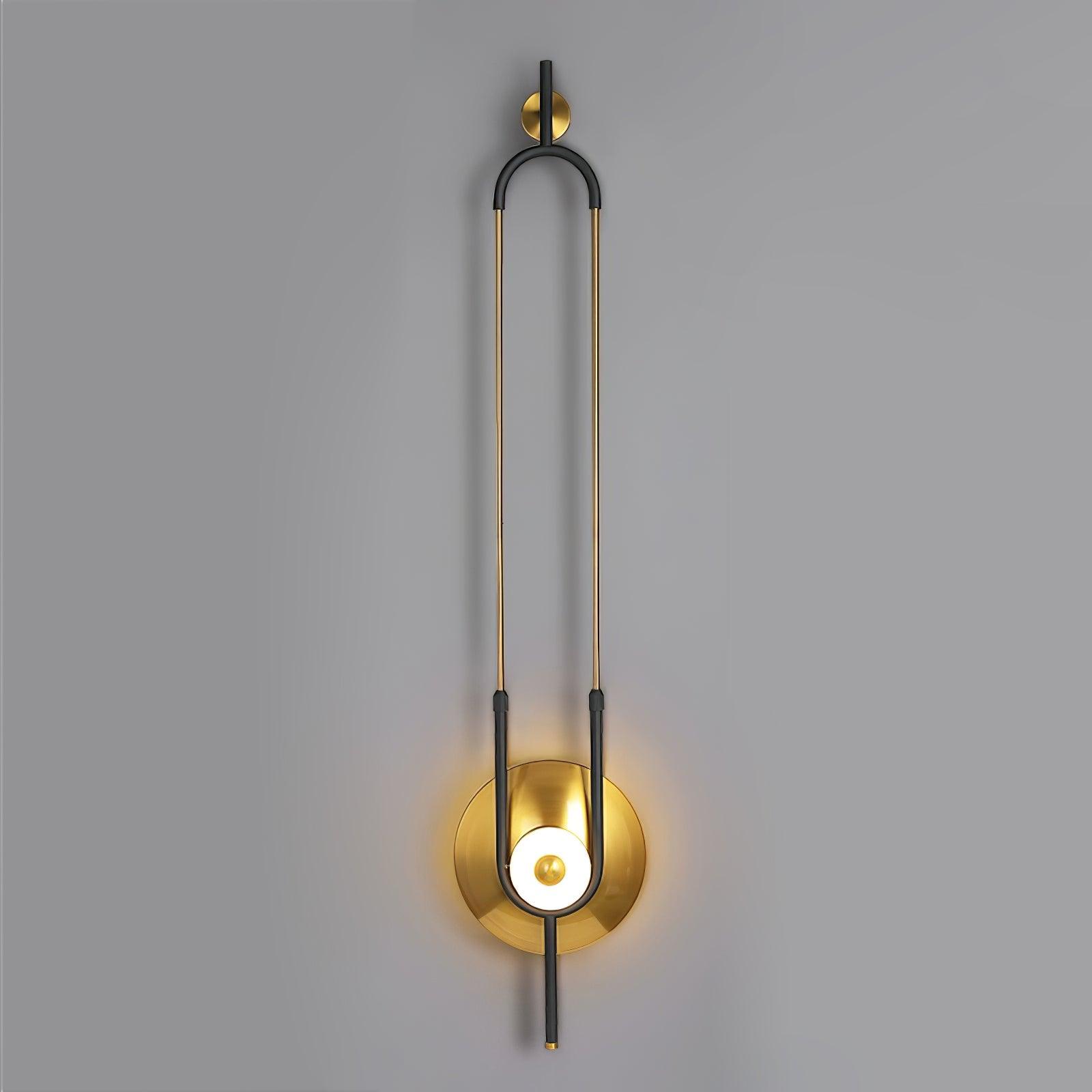 Close frontal gold-and-black loop wall light with glowing ring and gold disc on grey background