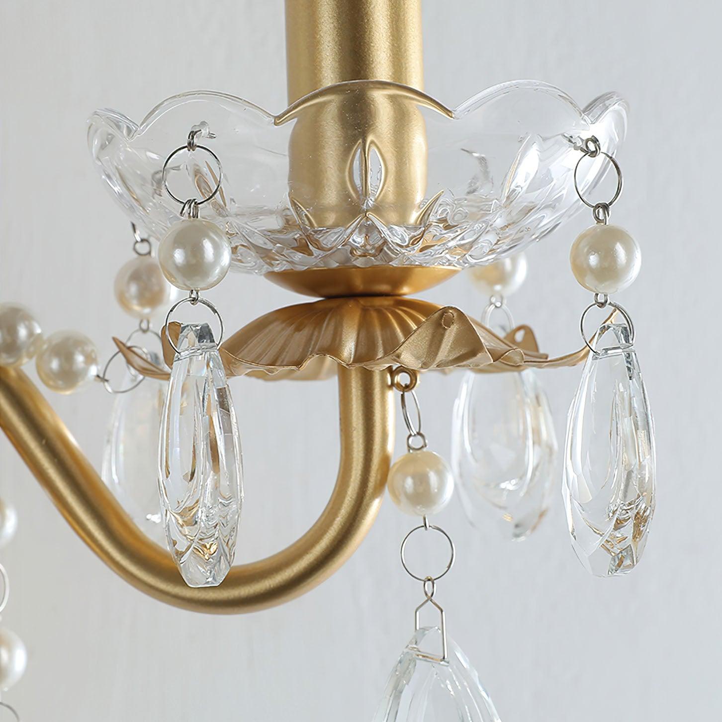Unlit clear scalloped bowl with pale pearl-like beads, small rings and faceted transparent drops above curved gold arm