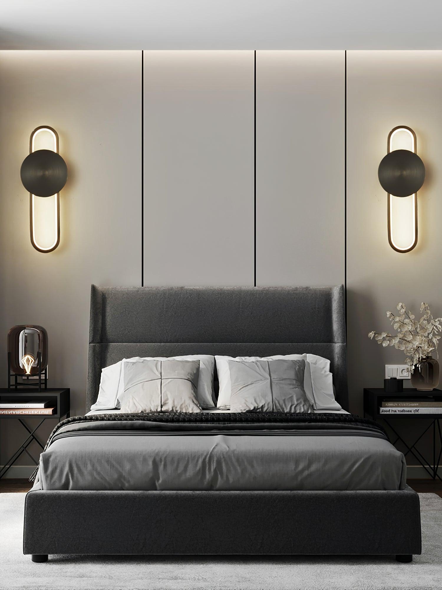Two Black finish Allen wall lights with gold-tone loops on either side of a grey bed and headboard