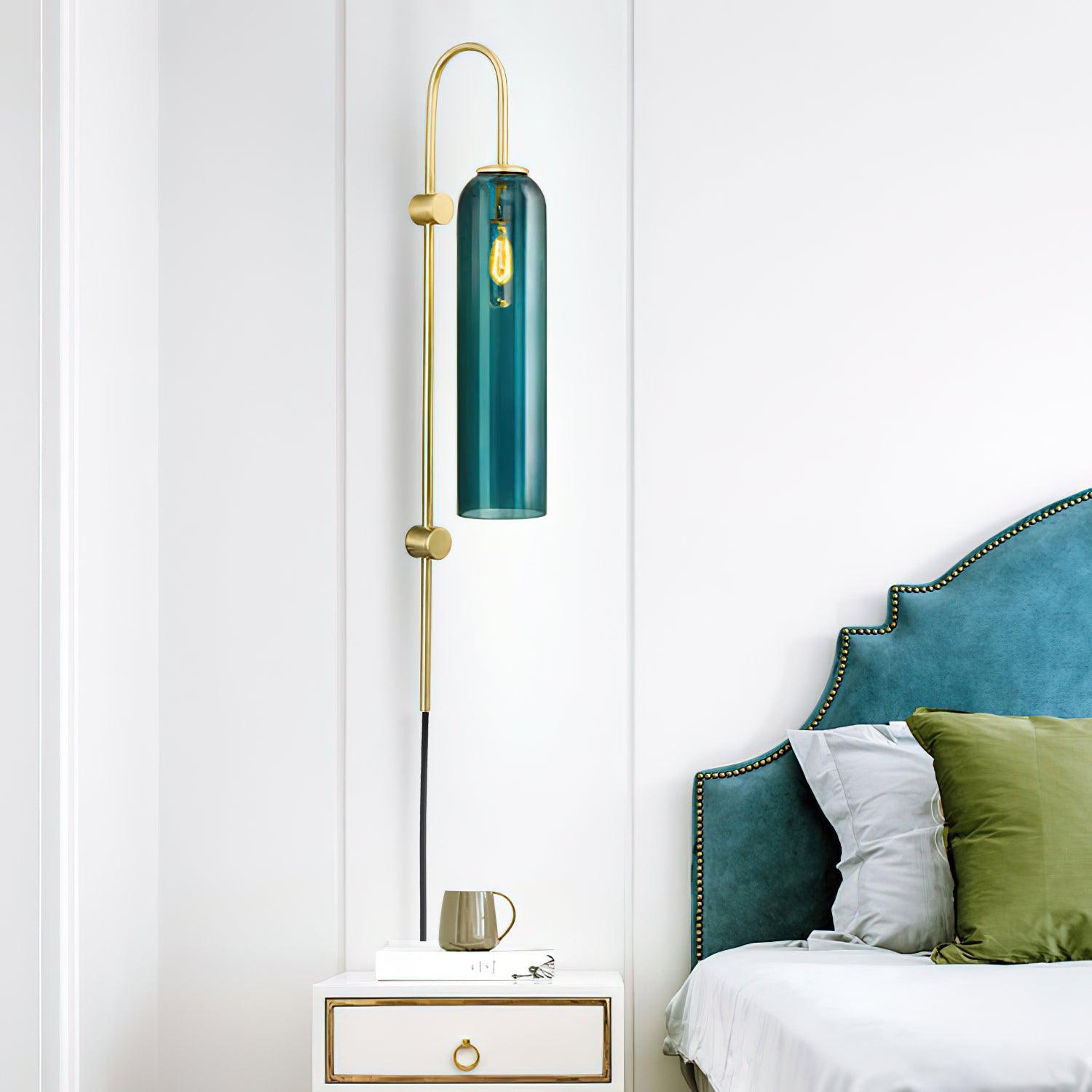 Dark teal tube wall fixture beside a bed