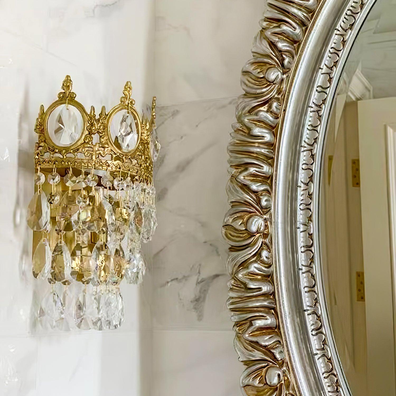 Crystal wall sconce beside an ornate mirror