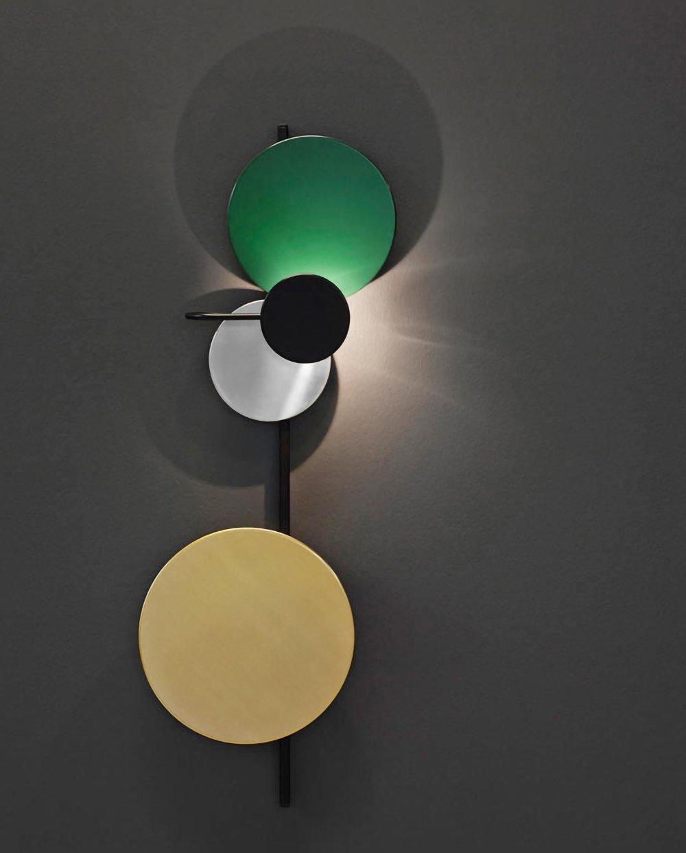 Green disc lamp reflecting light on a dark wall