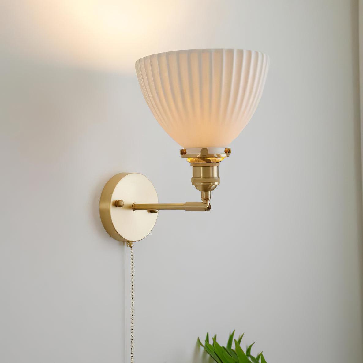 White pleated shade shown facing upward above a brass arm, with round wall plate and hanging chain