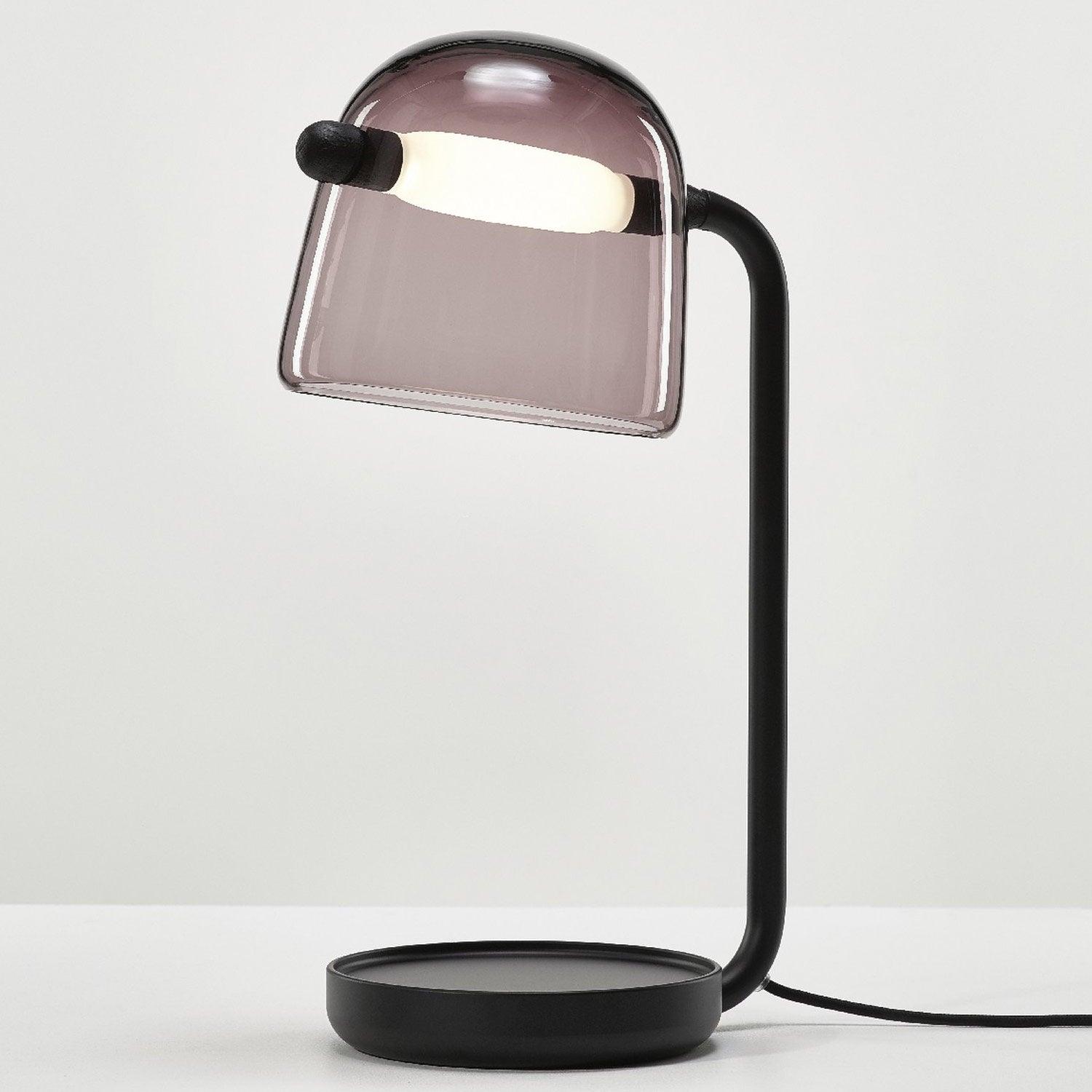 Mona table lamp with a tinted glass shade, black curved support and round base